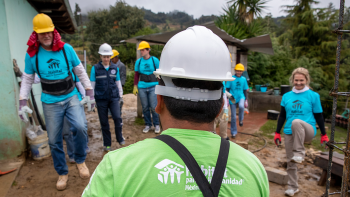 Group of six Global Village volunteers in Habitat shirts on a build site in Mexico.