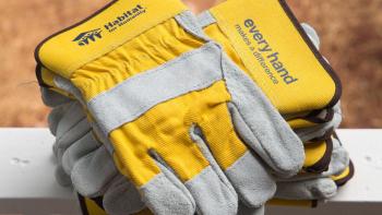 Close-up of yellow Habitat-branded work gloves on a porch railing.