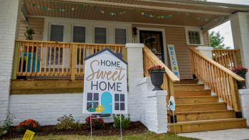 Front of Habitat house with focus on a yard sign that reads "Home Sweet Home"