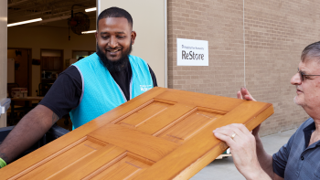 ReStore staff member helping man carry donated door