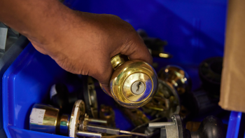 A hand putting a doorknob into a bin with other doorknobs for sale.
