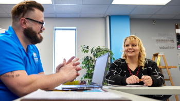 Habitat staff member and woman talking to each other in a classroom setting