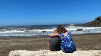 Two children embracing on the beach.
