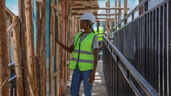 Woman on a construction site in Kenya examines natural wood materials.