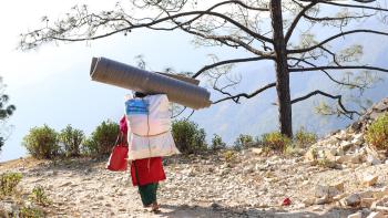 Person carrying items in mountainous landscape.