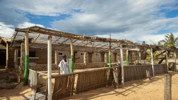 Alex stands among the ruins of a home that has been affected by climate change.