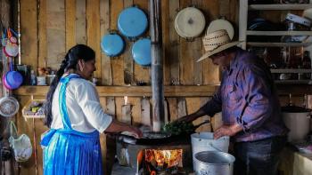 Imelda and her partner stand with a stove between them as they prepare a meal.