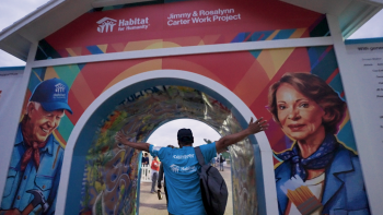 Volunteer walking into entrance tunnel of Carter Work Project decorated with mural of the late President and Mrs. Carter.