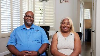 Bonnie and George sit in chairs facing the camera and smilng.