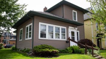 A grey house in a lush green yard.