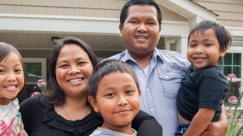 Two parents holding their three children and smiling.