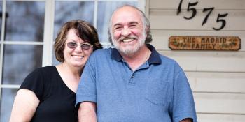 Senior couple posing together in front of their home