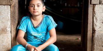 Young boy sits in doorway.