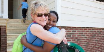 Volunteer hugs homeowner in front of new home