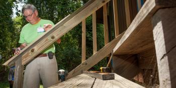 Volunteer measuring wood on a Habitat home repair site.