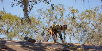 man in safety gear repairing a roof.