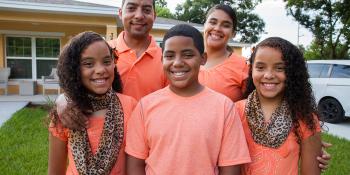 Carlos, sisters Janerys and Jarelys and parents Neryann and Javier stand in front of their Habitat home in matching shirts.