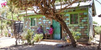 colorful house in Kenya surrounded by trees build with help of micro loans