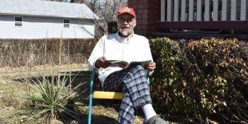 Kenneth sitting outside his home.