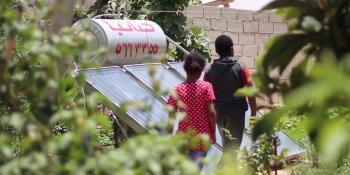 Photo: two children walking in green garden with solar panels