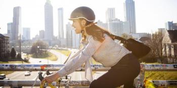 Woman riding bike in city smiling.