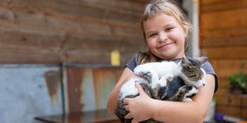 Miroslaw's daughter holding their pet cat.