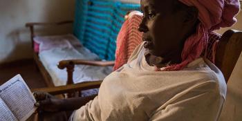 Photo: beneficiary of housing microfinance studying her book with payments