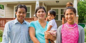 A family stands in front of their home.