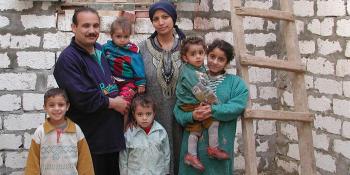 Photo: a family with 5 children, a new wall of their future house in the background