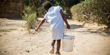 Zambian child carrying bucket of water