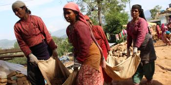 Photo: women carrying bricks together in a rug