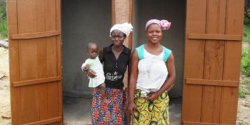 Photo: Two women and a child in front of a newly constructed latrine