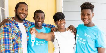 Krushetta holding her house keys with her three sons at her house dedication.