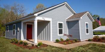 New Habitat house with blue siding and a red door.