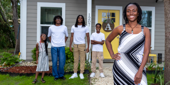 Smiling family of five standing in front of new home