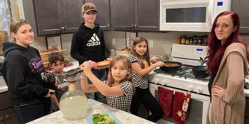 Mother and five children cooking a meal together in their kitchen
