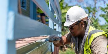 A Fijian community member painting a home's porch
