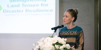 Anna, a cohort, speaks at a podium in front of a projected slideshow.