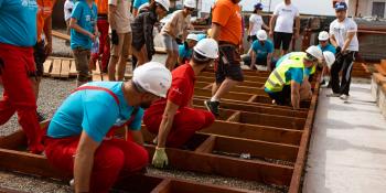 Volunteers lifting a wall from the ground on build site