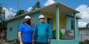 Elizabeth and Javier stand in front of the blue home they helped work on.