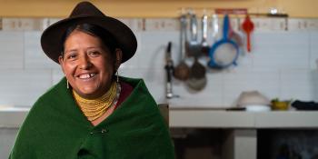 A woman shown from the waist up in her home kitchen.