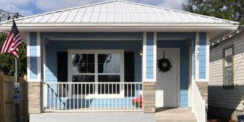 Photo: A blue house with a white roof and a front gated pation.