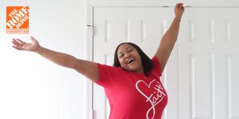 Woman in pink shirt with her arms in the air in excitement.