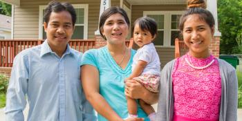 A family stands in front of their home.