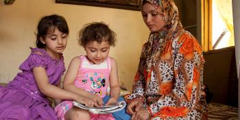 Inside a flat in Lebanon - two girls and their mother reading a book together 