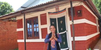 Nirmala standing in front of a brick house.