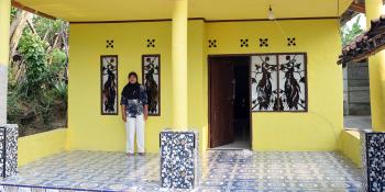 Nurhayati standing in front of her new home in Indonesia that she built with housing finance loans