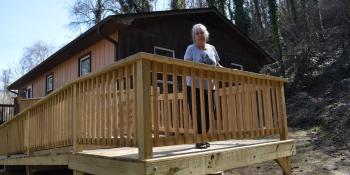 Homeowner stands on new wooden ramp. 