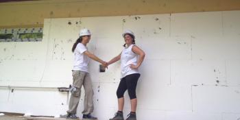 Two volunteers shaking hands on a construction site in hard hats