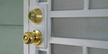 A close-up of a golden door-knob on a white wooden door.